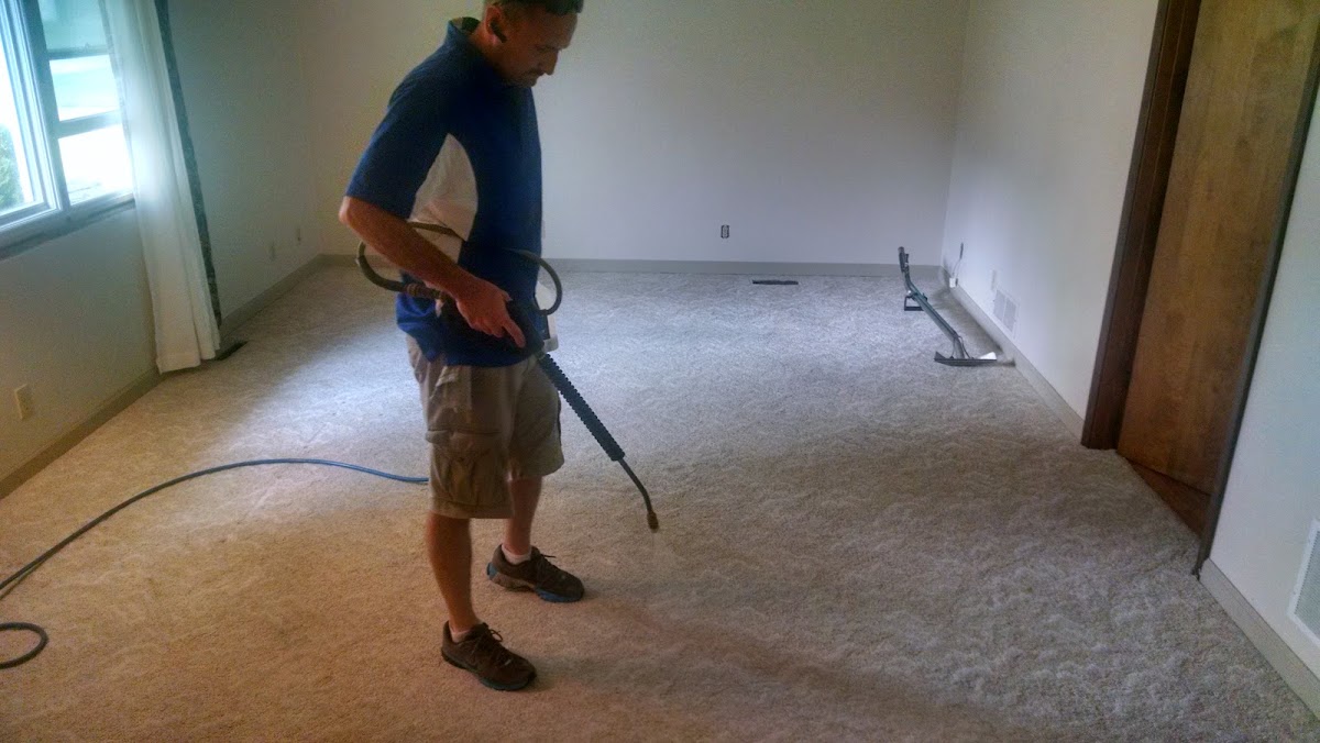 Carpet being cleaned with a wand in an empty room